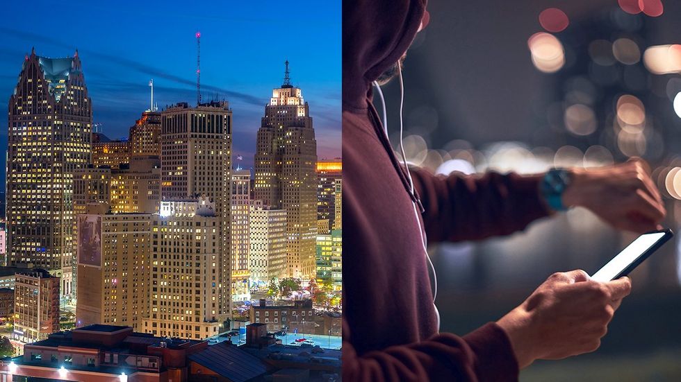 detroit city skyline night view person in hoodie with cellphone checking their watch