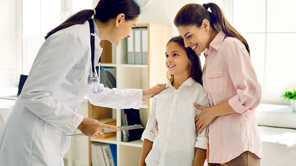 doctor comforting transgender teen with mother