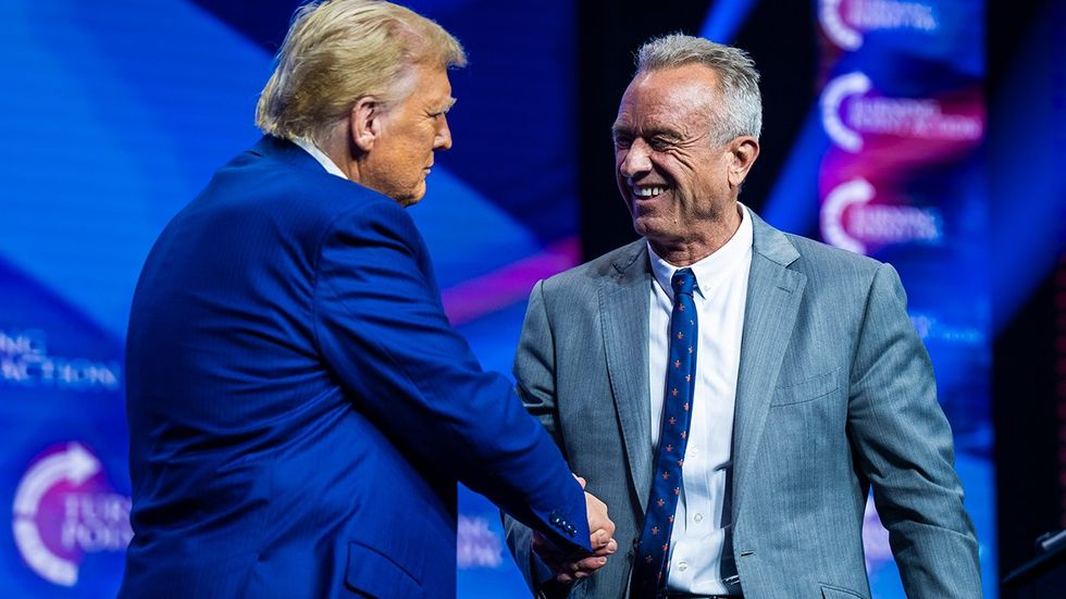 Donald Trump shakes hands with Robert F Kennedy Jr at a Turning Point Action Rally in Duluth GA