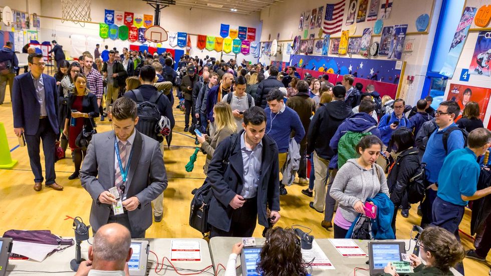 Election officials check voters identification highschool gym