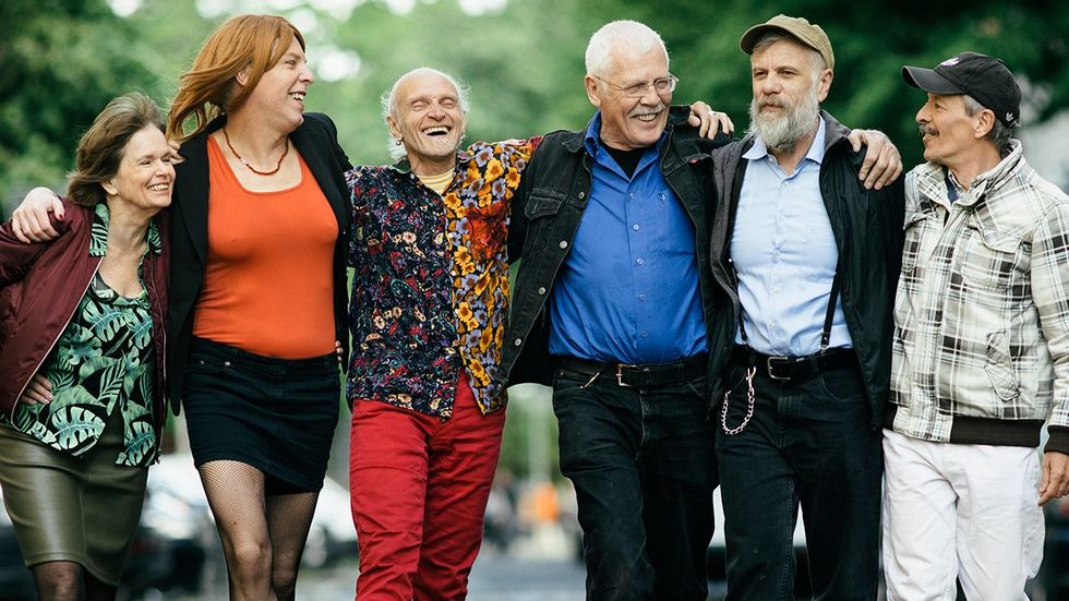 group middle age and senior citizen queer people arms crossed walking down street together