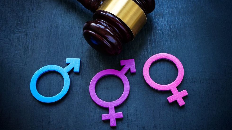 judges gavel resting on table with gender marker symbols