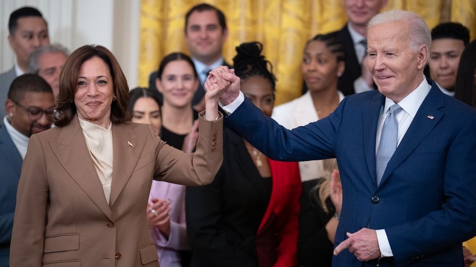 Kamala Harris and Joe Biden at event holding hands and smiling