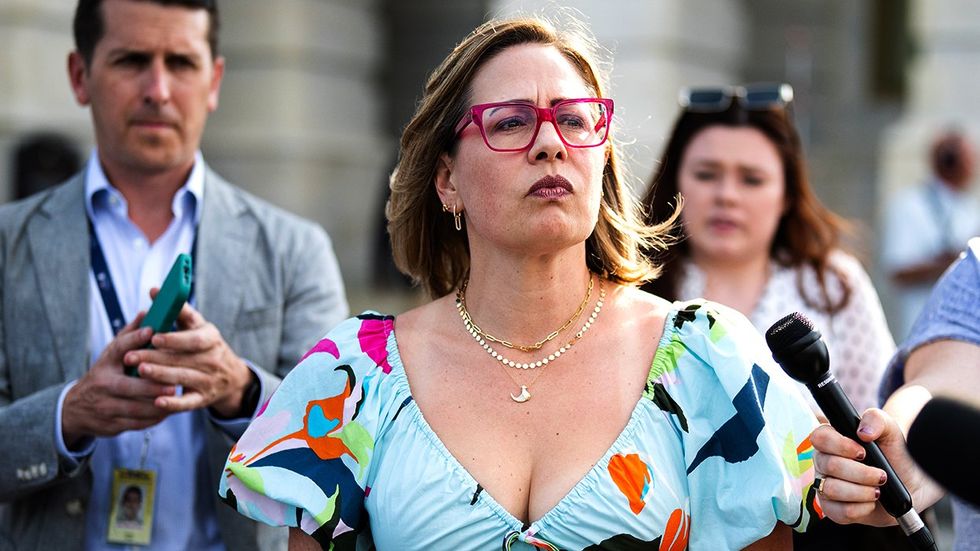 Kyrsten Sinema surrounded by reporters leaves the US Capitol after a vote