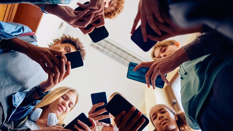 Low angle view LGBTQIA group of high school students using their cell phones