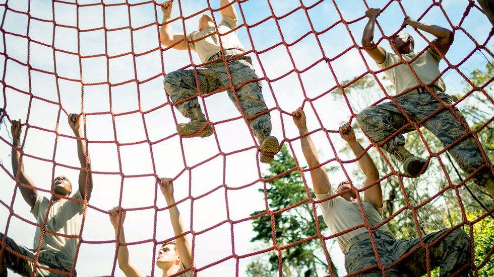 Military soldiers climbing rope during obstacle course in boot camp