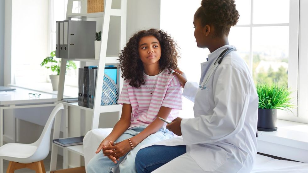 nervous queer Black teen being comforted by doctor during appointment