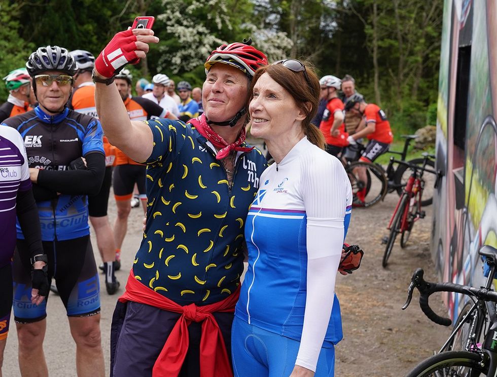 Philippa York in blue and white poses for selfies with other cyclists