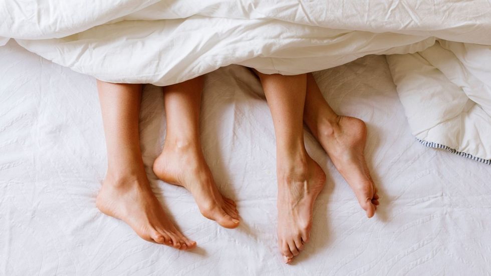 Photo of two women's pair of feet in bed