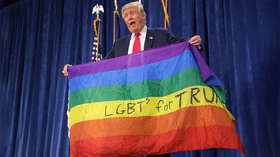 Republican presidential nominee Donald Trump holds an LGBT rainbow flag given to him by supporter Max Nowak during a 2016 campaign rally