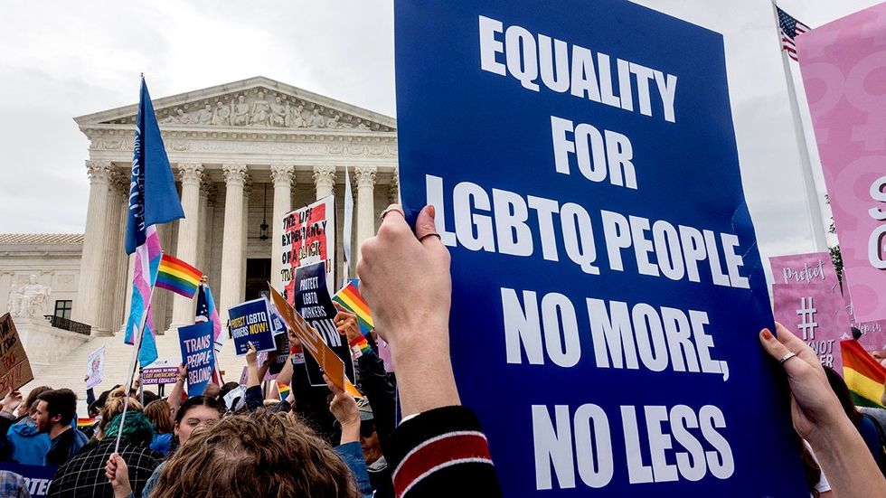 SCOTUS protest sign equaity for LGBTQ people rainbow and transgender flags waiving