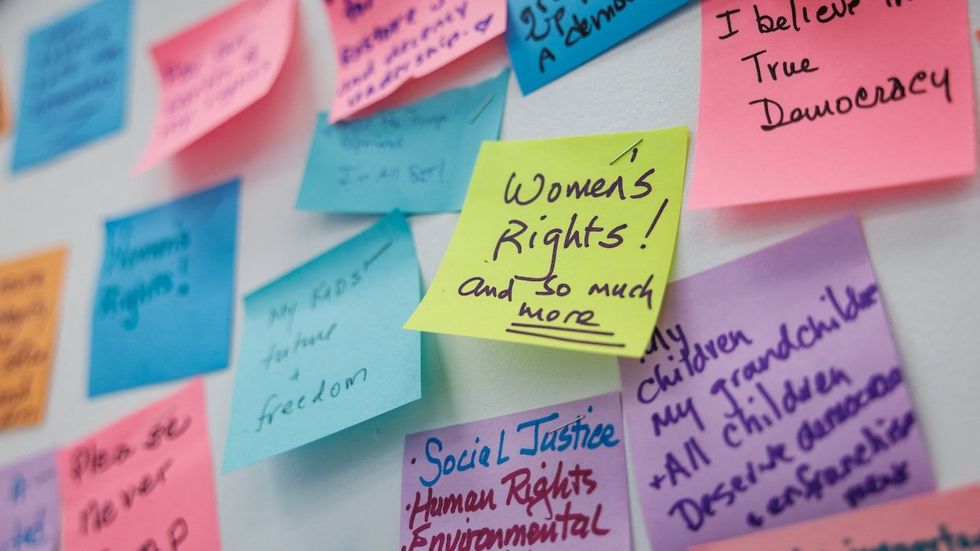 Sticky notes that detail why people are voting for Kamala Harris. One in focus says "women's rights and so much more."