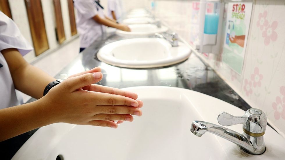 student washing hands school bathroom