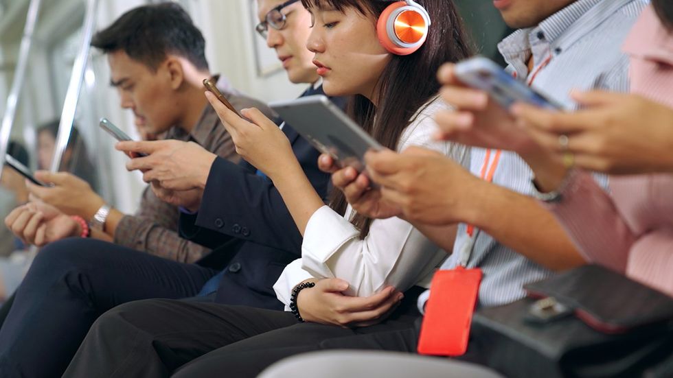 subway crowd using cell phones headphones tablets technology focused