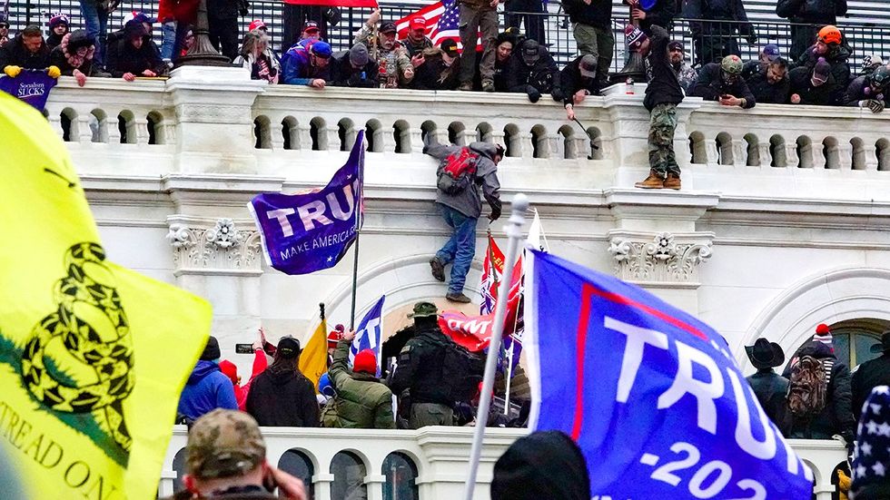 Trump supporters wave flags and climb the surrounded Capitol building Washington DC on January 6 2021 insurrection