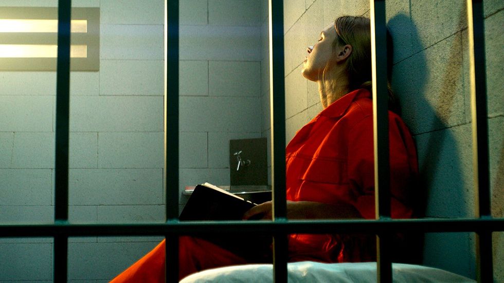 woman reading book jail cell