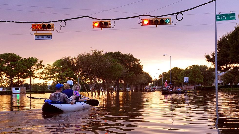 Working traffic lights over flooded Houston Texas streets and storm rescue boats with people at sunset