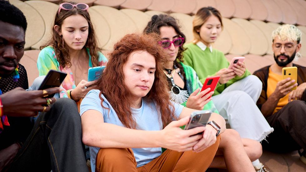 young queer friend group concerned looking at cellphones