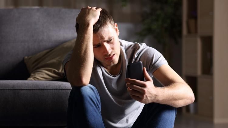 Man depressed looking at his phone